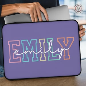 May include: A purple laptop sleeve with the name "EMILY" in colorful block letters and a cursive font overlay. The sleeve has a black border and is designed to protect a laptop.