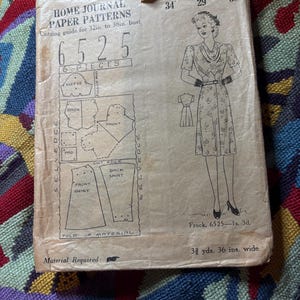 May include: A vintage Home Journal paper pattern envelope, number 6525, for a frock. The tan paper shows a line drawing of a dress, six pattern piece diagrams, and measurements of 34-inch bust, 29-inch waist, and 38-inch hips, with 3 3/8 yards required.