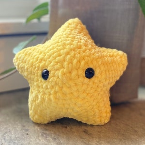 May include: A yellow crocheted star-shaped plush toy with black button eyes.