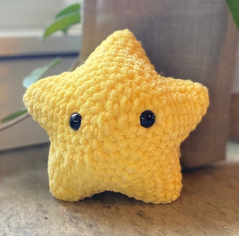 May include: A yellow crocheted star-shaped plush toy with black button eyes.