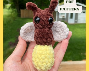 May include: A crocheted firefly amigurumi toy with brown and white fur, yellow yarn for the light, and black eyes. The toy is being held in a hand. The text "PDF PATTERN" is visible in the background.