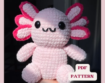Op de afbeelding: Roze gehaakte axolotl knuffel met rode oren. Het speelgoed heeft zwarte ogen en een kleine zwarte mond. De tekst "PDF PATTERN" is zichtbaar in de afbeelding.