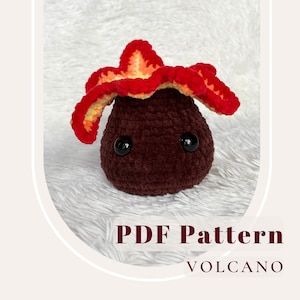 Può includere: Schema all'uncinetto per un adorabile giocattolo di peluche vulcano. Il peluche è marrone con lava rossa e arancione e occhi neri. Lo schema è disponibile per il download in PDF.