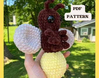 Puede incluir: Patrón de crochet para un juguete amigurumi de luciérnaga. La luciérnaga es marrón con alas blancas y una luz amarilla. El patrón está disponible para descargar en PDF.