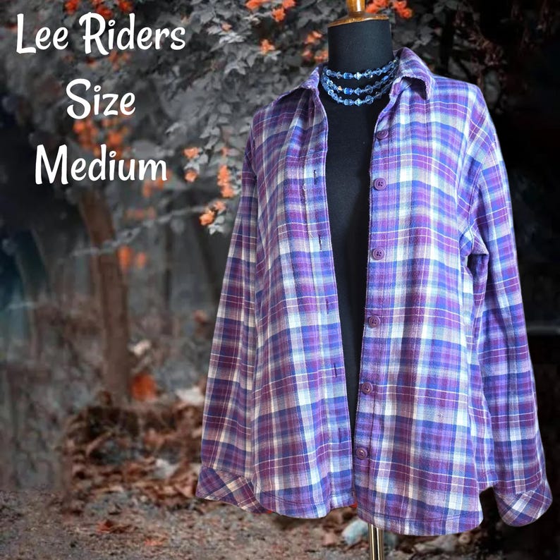 May include: A long-sleeve button-down shirt featuring a purple, white, and blue plaid pattern. The shirt is displayed on a mannequin wearing a blue beaded necklace. Text on the image reads: Lee Riders Size Medium.