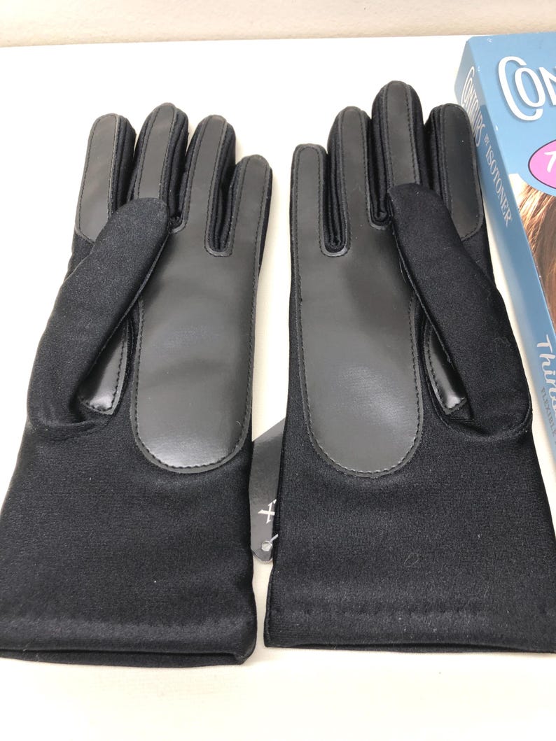 Op de afbeelding: Een paar zwarte handschoenen met leren accenten op de handpalmen en vingers. De handschoenen zijn gemaakt van een zachte, donkere stof en hebben een label. De handschoenen zijn ontworpen voor koud weer.