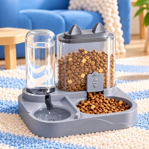May include: A gray pet feeder with a clear water bottle and a clear food storage container featuring cat-ear-shaped accents on the lid. The base includes a water bowl and a food bowl filled with brown kibble, with a manual slider mechanism.