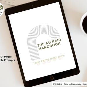May include: A digital tablet displays "THE AU PAIR HANDBOOK" with a stylized arch design. The text "Enter Family Name Here" is below the title. The image also includes a coffee cup, a stylus, and the text "Over 50+ Pages of Editable Prompts."
