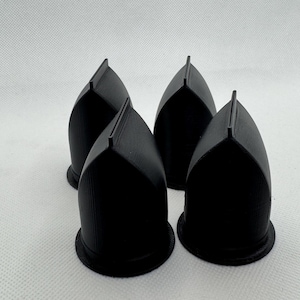 以下が含まれることがあります： 平らな底を持つ黒いプラスチック製のドーム型のオブジェクトが4つあります。オブジェクトは半円形に配置されています。