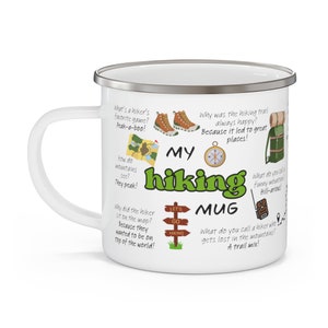 May include: White enamel camping mug with a green "My Hiking Mug" design. The mug features illustrations of hiking boots, a compass, a map, a backpack, and a sign that says "Let's Go Hiking". The mug has text around the design with hiking puns.