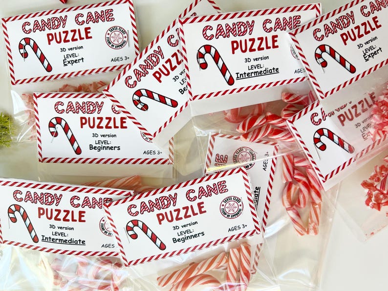 Puede incluir: Varias bolsas de pl&aacute;stico transparente llenas de bastones de caramelo rojos y blancos y piezas de rompecabezas. Cada bolsa tiene una etiqueta que dice "Candy Cane Puzzle" con un nivel de dificultad y un rango de edad.