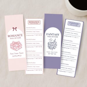 May include: Four decorative bookmarks with the text "Romance Hall of Fame" and "Fantasy Hall of Fame". The bookmarks are pink and purple with illustrations of books, bows, and a sword. A white coffee cup is in the background.