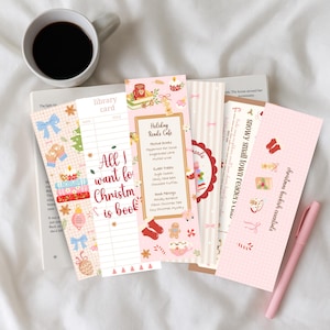 May include: A collection of Christmas-themed bookmarks with festive designs, including bows, mittens, and ornaments. One bookmark reads "All I want for Christmas is book." A cup of coffee and a pen are also present.