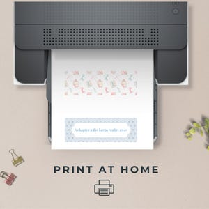 May include: A printer printing a white sheet of paper with a patterned design and the text "A chapter a day keeps reality away". The paper has a light blue border with white dots. The image also includes the text "PRINT AT HOME".