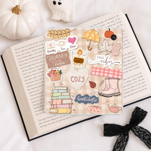 May include: A square tablet case featuring a beige and white checkered pattern decorated with various autumn-themed stickers including a stack of books, a pumpkin basket, a yellow umbrella, a candle, pink rain boots, and text reading Fall vibes.