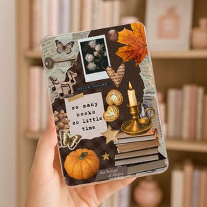 Puede incluir: Una funda protectora transparente para lector electrónico con un collage de elementos otoñales que incluye una calabaza, una pila de libros, una vela encendida en un candelabro de latón, una hoja de arce, mariposas, una llave y el texto so many books so little time.