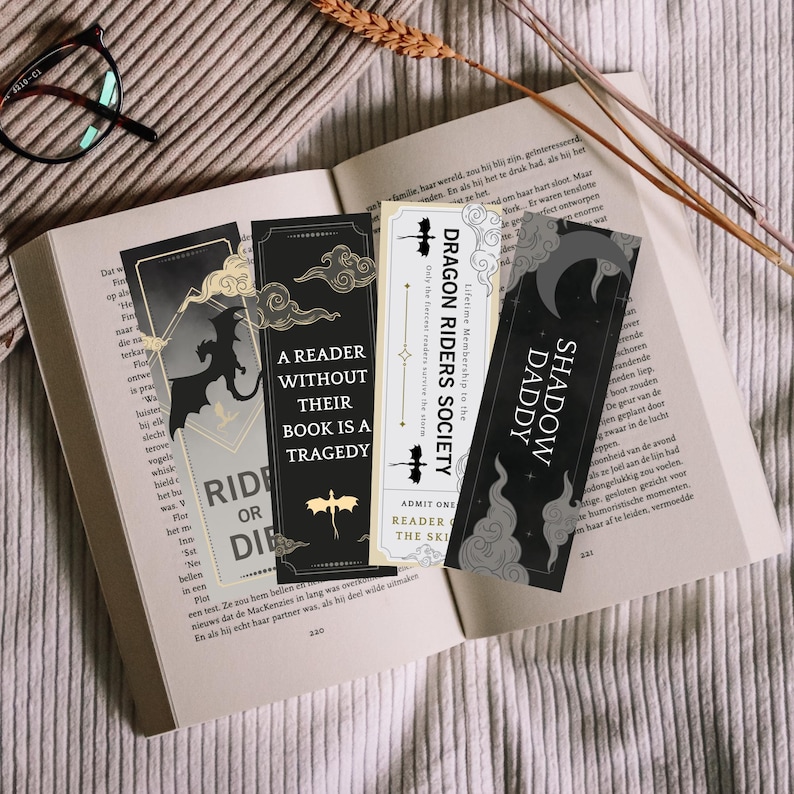May include: Four black and white bookmarks with different designs. The bookmarks feature dragons, clouds, and text. The text on the bookmarks reads "Dragon Riders Society", "Shadow Daddy", "A Reader Without Their Book Is A Tragedy", and "Ride or Die".