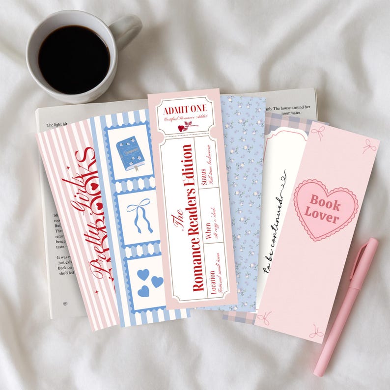 May include: A collection of decorative bookmarks with various designs, including stripes, floral patterns, and text. One bookmark reads "Pretty Girls Books," another "The Romance Readers Edition," and a third says "Book Lover." A cup of coffee and a pen are also present.