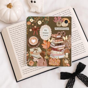 May include: A square tablet case featuring a brown background with illustrations of a stack of books, a coffee cup with heart latte art, a person reading, cinnamon rolls, pumpkins, autumn leaves, a candle, and text reading My Happy Place.