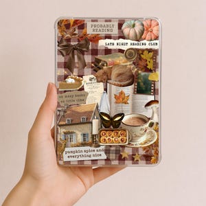 May include: A clear rectangular phone case featuring a collage of autumn-themed imagery, including a brown bow, a sleeping cat, a house, a cup of coffee, pumpkins, and text reading "PROBABLY READING," "LATE NIGHT READING CLUB," and "pumpkin spice and everything nice."