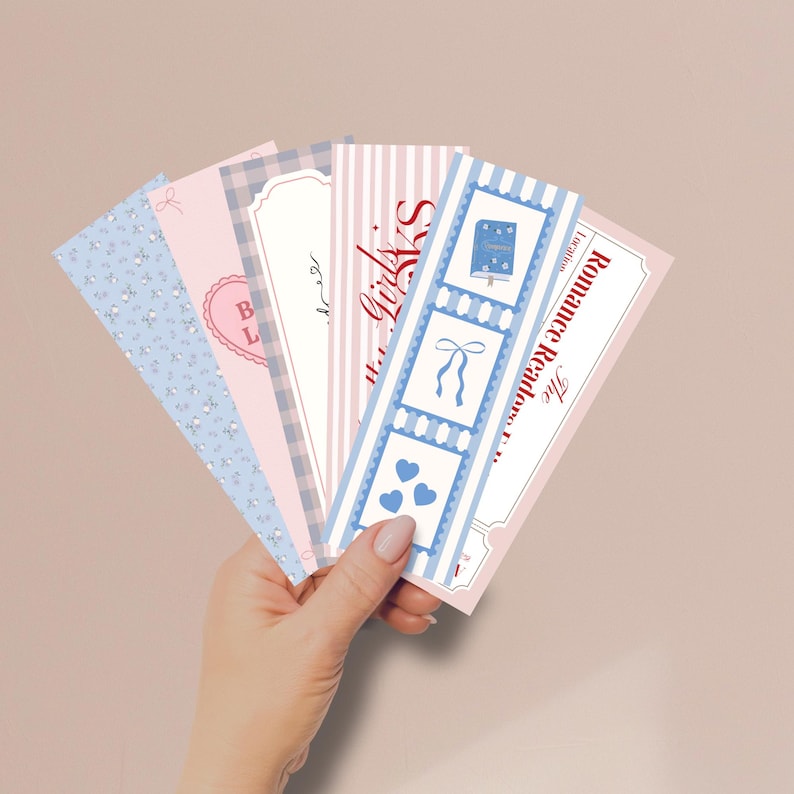 May include: A collection of decorative bookmarks in pastel colors. Designs include floral patterns, hearts, stripes, and the text "Girls" and "The Romance Readers". Each bookmark has a unique design with bows and hearts.
