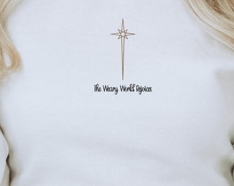 May include: White sweatshirt with a star and cross graphic and the text "The Weary World Rejoices".