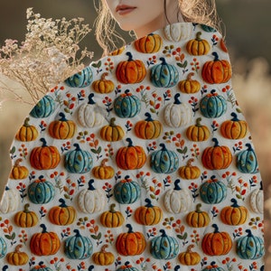 May include: A white fabric with a repeating pattern of orange, blue and white pumpkins. The pumpkins are arranged in a staggered pattern and are surrounded by small green leaves and red berries.