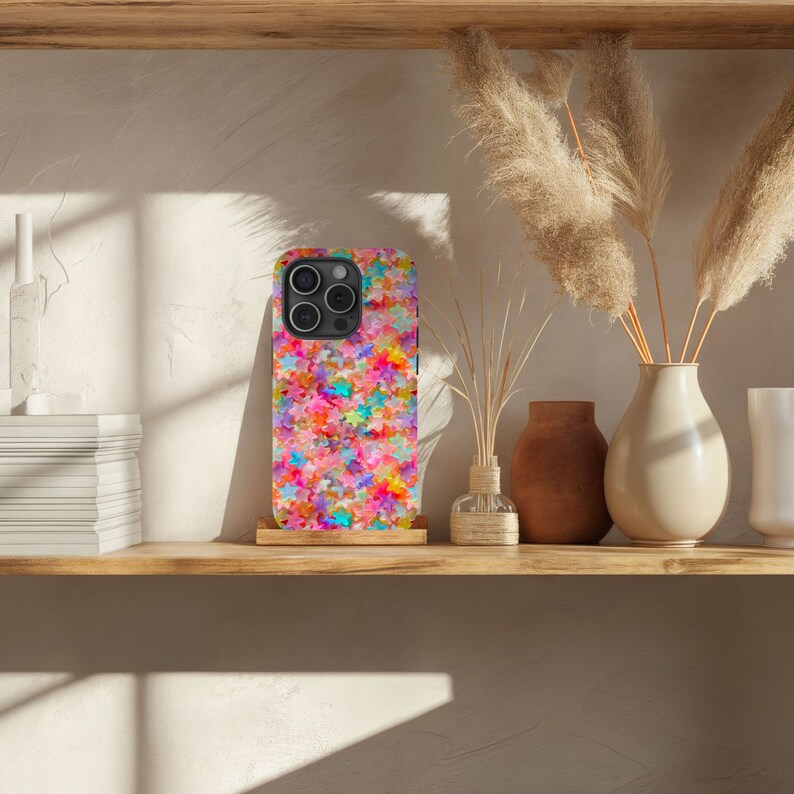 May include: A colorful phone case with a pattern of multi-colored stars. The case is designed for an iPhone with a camera bump.