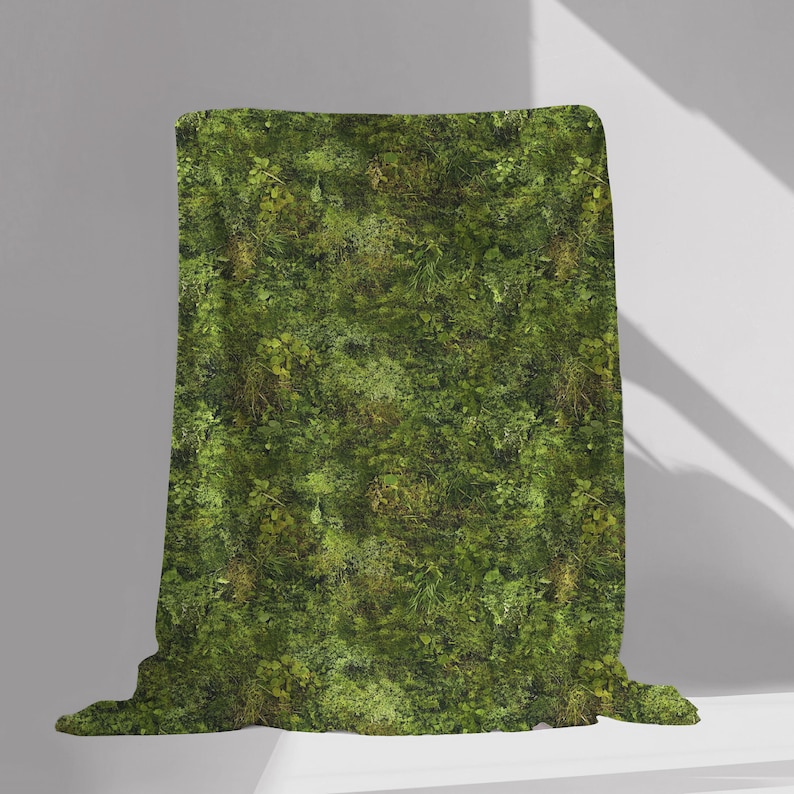May include: A green throw blanket with a mossy pattern. The blanket is folded and displayed on a white surface.