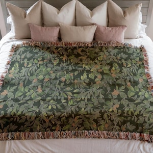 May include: A green throw blanket with a floral pattern. The blanket has a fringe border and is made of a soft, woven fabric.
