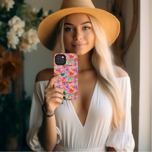 May include: A woman is holding a pink and white phone case with a colorful star pattern. The case is designed for an iPhone.