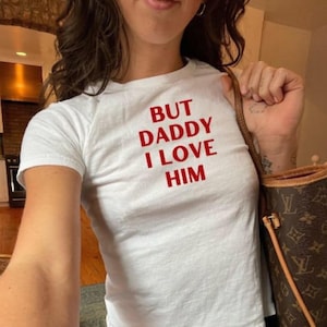 May include: White t-shirt with red text that reads "But Daddy I Love Him".