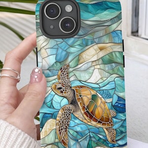 May include: A phone case with a stained glass design featuring a sea turtle swimming in blue and green water. The case has a black border and a camera cutout.