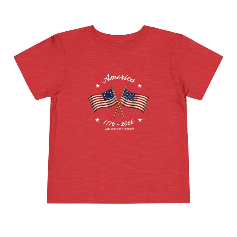 May include: Red t-shirt with the word "America" above two crossed American flags. The flags are from the Revolutionary War era. The text "1776 - 2026" and "250 Years of Freedom" are below the flags. The shirt is made of a soft material.