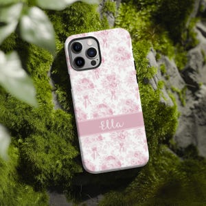 Op de afbeelding: Een witte telefoonhoes met een roze bloemenpatroon en de naam "Ella" gedrukt op een roze streep.