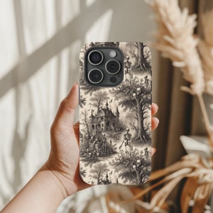Puede incluir: Una funda de iPhone blanca con un estampado en blanco y negro de una casa encantada espeluznante, &aacute;rboles y esqueletos. La funda tiene una protuberancia de c&aacute;mara negra con cuatro lentes.