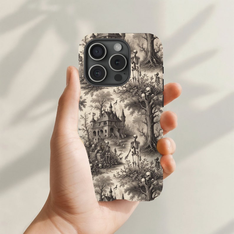 Puede incluir: Una funda de tel&eacute;fono en blanco y negro con un dise&ntilde;o de Halloween espeluznante. La funda presenta una casa encantada, esqueletos y &aacute;rboles.
