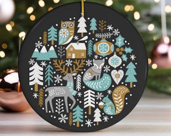 Puede incluir: Un adorno navideño redondo negro con un diseño de inspiración escandinava. El adorno presenta un ciervo, un zorro, un búho, una ardilla y otras criaturas del bosque en un patrón caprichoso con copos de nieve y árboles. El adorno está decorado con colores dorados, blancos y azules.