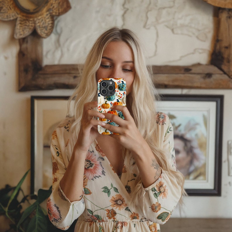 Peut inclure: Une coque de t&eacute;l&eacute;phone iPhone blanche avec un motif de citrouilles color&eacute;es. La coque pr&eacute;sente une vari&eacute;t&eacute; de citrouilles orange, vertes et bleues avec des tiges et des feuilles blanches.
