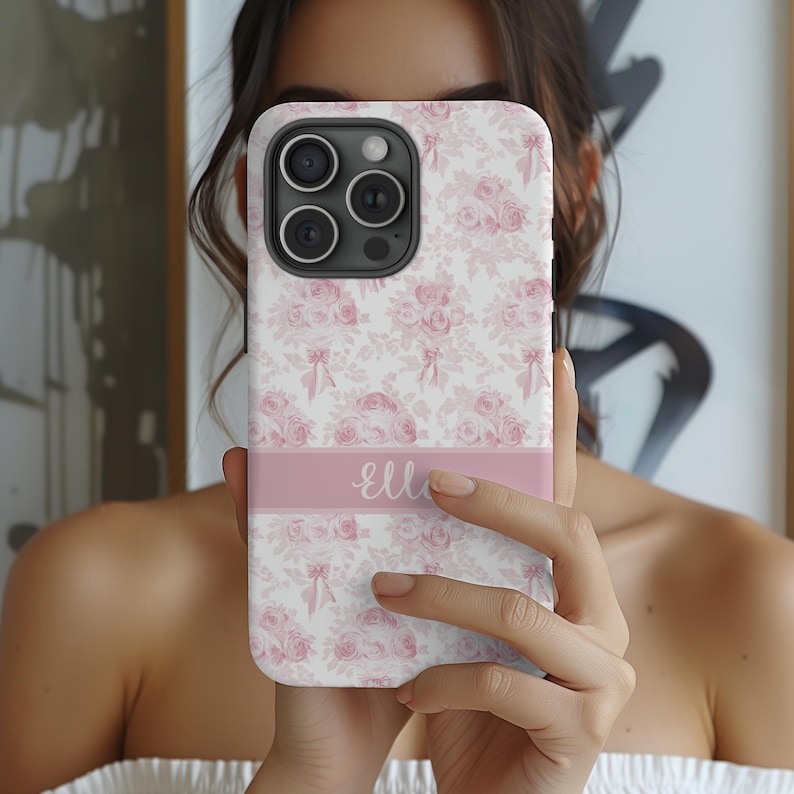 Op de afbeelding: Een roze en witte bloemen telefoonhoesje met een roze band aan de onderkant waarop "elle" staat.