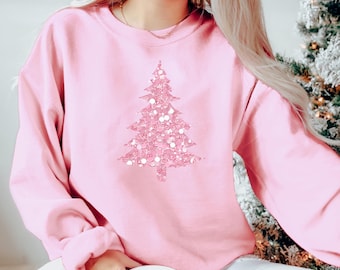 May include: A pink sweatshirt with a sparkly pink Christmas tree design.