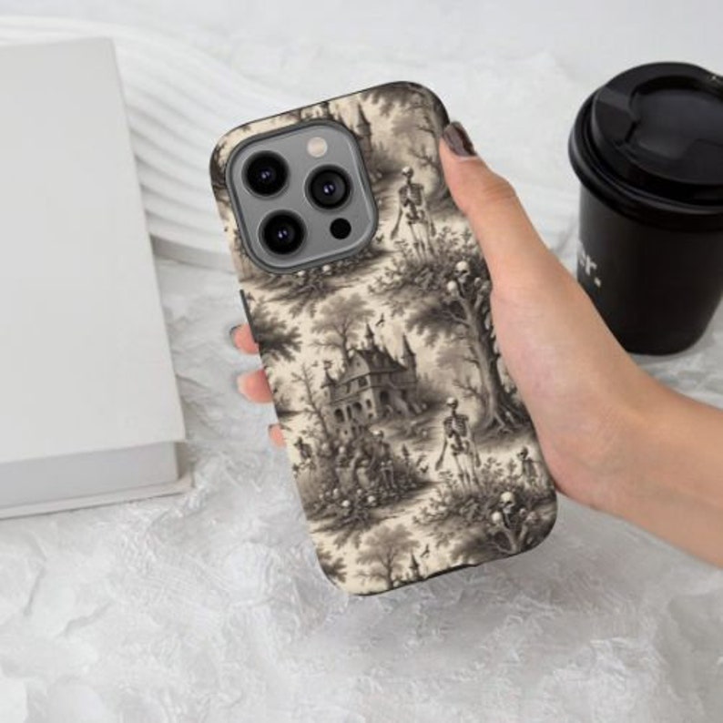 Puede incluir: Una funda para tel&eacute;fono en blanco y negro con un patr&oacute;n de esqueletos en un dise&ntilde;o de inspiraci&oacute;n vintage y espeluznante. La funda presenta un patr&oacute;n repetitivo de esqueletos en un jard&iacute;n con un castillo en el fondo.