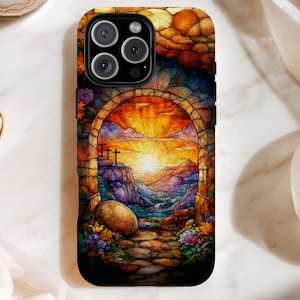 May include: A phone case with a stained-glass effect depicting an archway with a sunrise, three crosses, and a landscape. The case has a black border and a colourful, artistic design with a large stone and flowers.