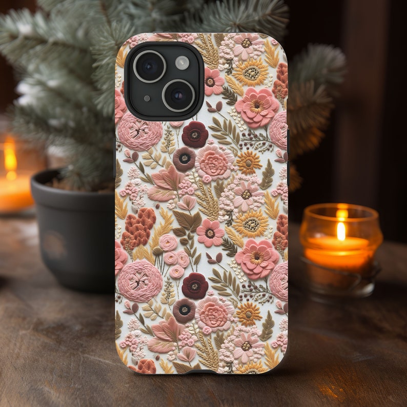 May include: A floral phone case featuring a detailed embossed design. The case showcases a variety of flowers in shades of pink, peach, and brown against a white background. The case has a camera cutout and is designed to fit a smartphone.