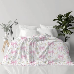 May include: White bedding with a pink bow and floral pattern.