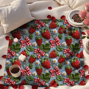 May include: A blue and white gingham fabric with a repeating pattern of red strawberries, green leaves, and white flowers. The strawberries are embroidered with a red and white gingham bow.