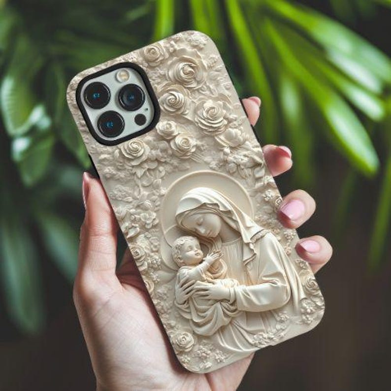 May include: A white phone case with a carved design of a mother and child. The design is reminiscent of a religious icon. The case has a black camera lens.