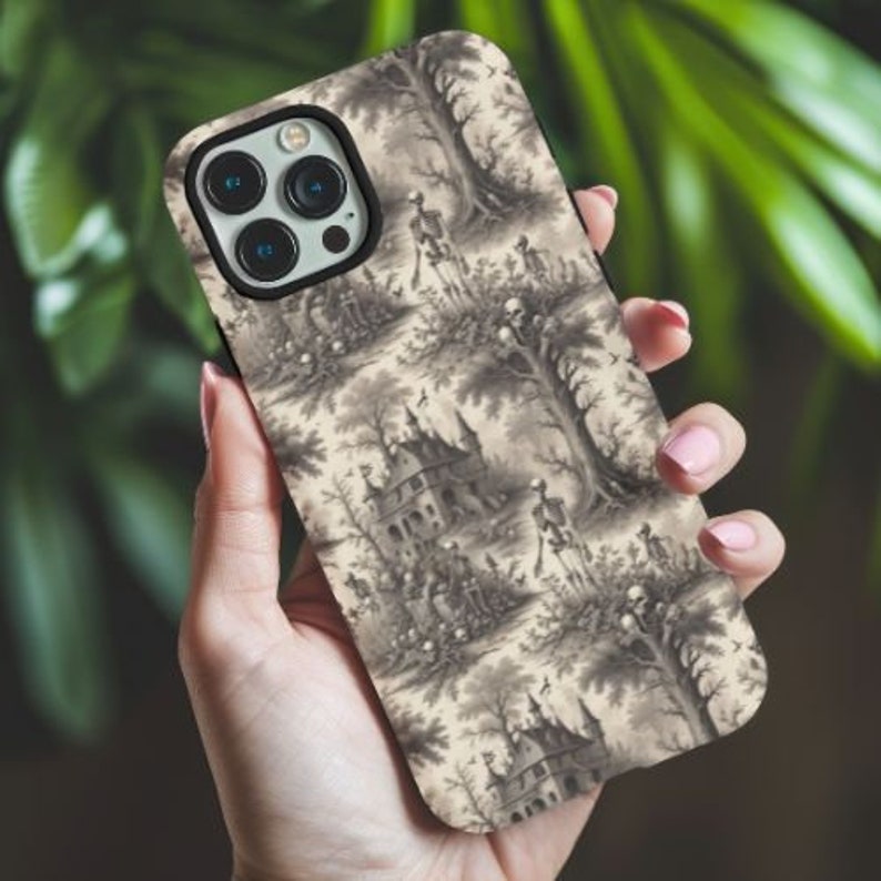 Puede incluir: Una funda de tel&eacute;fono negra con un estampado vintage de esqueletos en un jard&iacute;n. El estampado presenta un patr&oacute;n repetitivo de esqueletos, &aacute;rboles y casas.