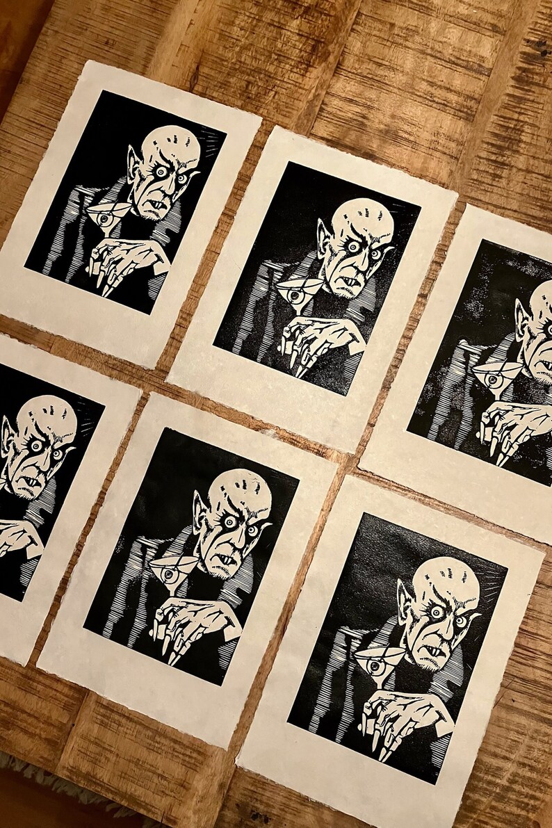 Schwarz/Weiss Linoldruck. Motiv: Nosferatu mit einem Glas Martiniin der Hand. Nosferatu trinkt diesen natürlich mit einem aufgespiessten Augapfel, anstelle einer klassischen Olive :). Der Druck ist handgezeichnet, handgedruckt und signiert.