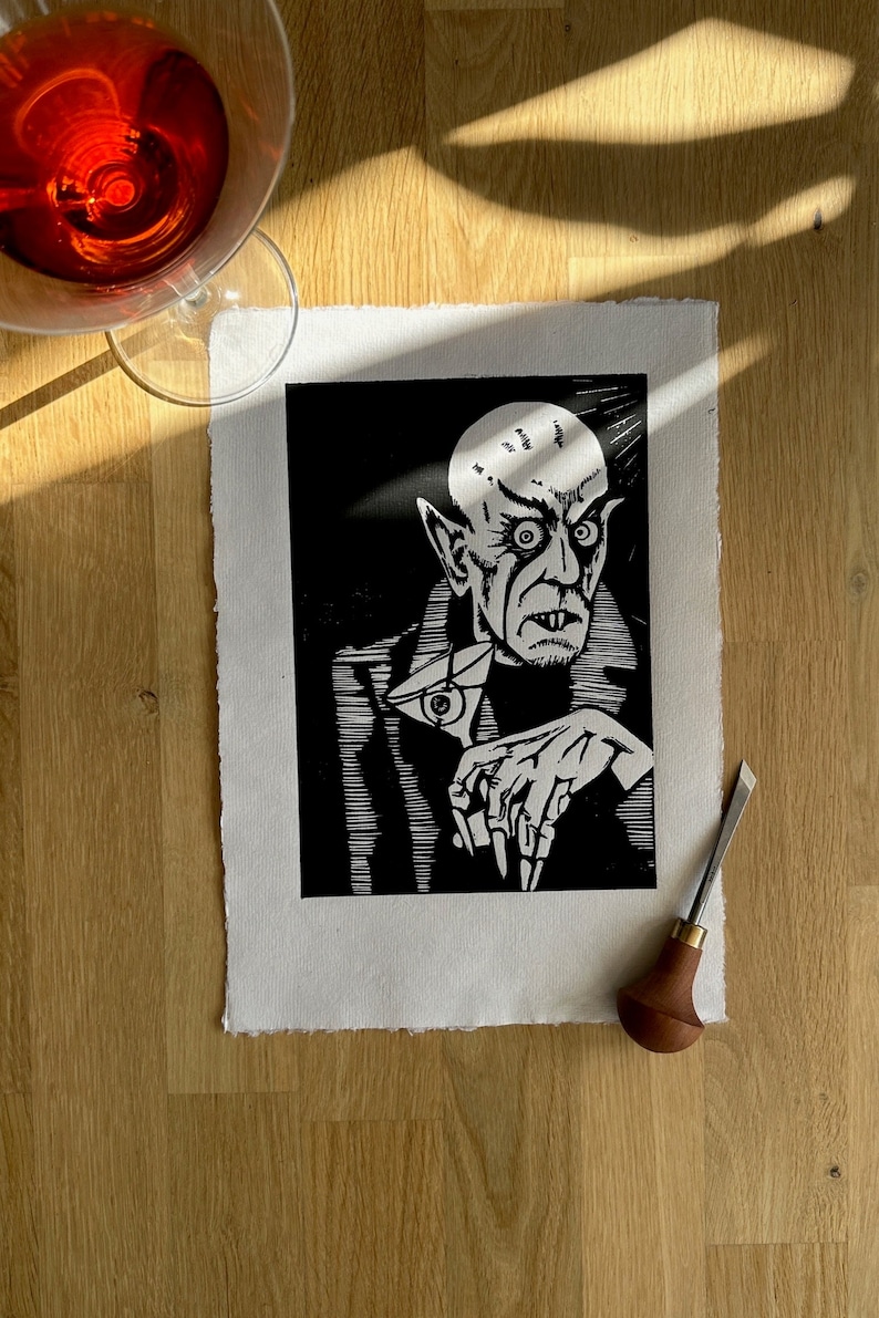 Schwarz/Weiss Linoldruck. Motiv: Nosferatu mit einem Glas Martiniin der Hand. Nosferatu trinkt diesen natürlich mit einem aufgespiessten Augapfel, anstelle einer klassischen Olive :). Der Druck ist handgezeichnet, handgedruckt und signiert.
